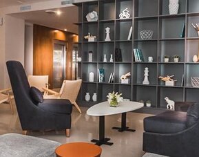 Hotel lobby with armchairs, coffee tables, decorative shelving and contemporary lighting at Howard Johnson Plaza Buenos Aires.