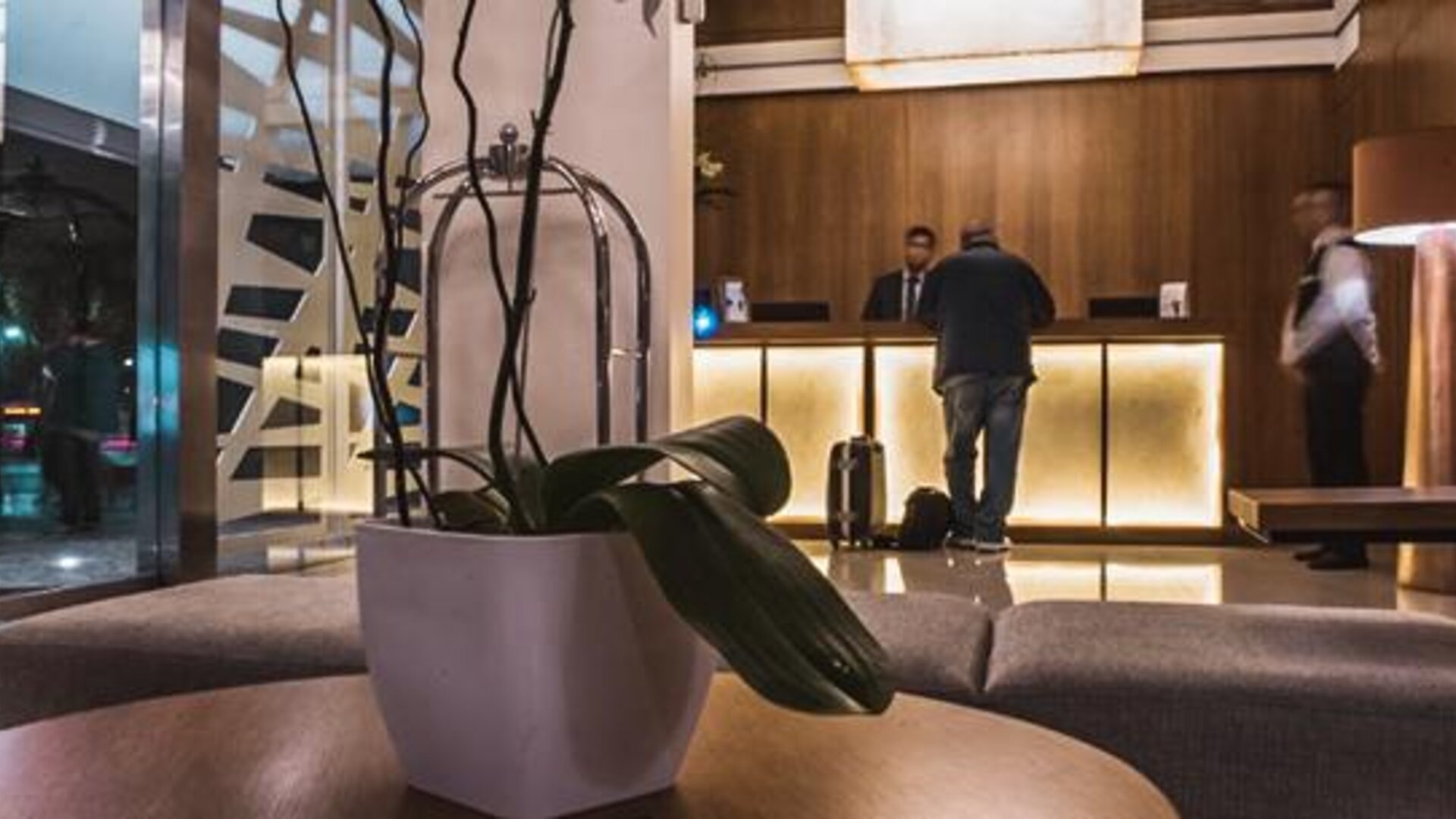 Reception area with a backlit front desk, decorative stone wall, seating and glass entrance at Howard Johnson Plaza Buenos Aires.