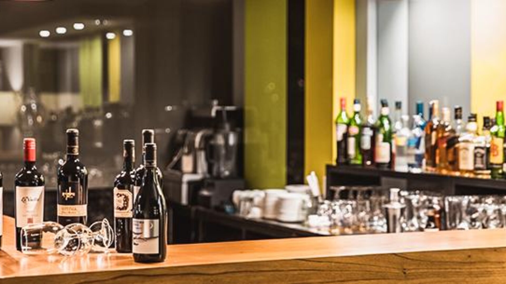 Hotel bar with wine bottles, glassware, a wooden counter and illuminated shelving at Howard Johnson Plaza Buenos Aires.