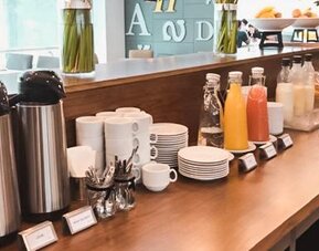 Breakfast coffee station with coffee machines, cups, saucers, juice bottles and pastries at Howard Johnson Plaza Buenos Aires.