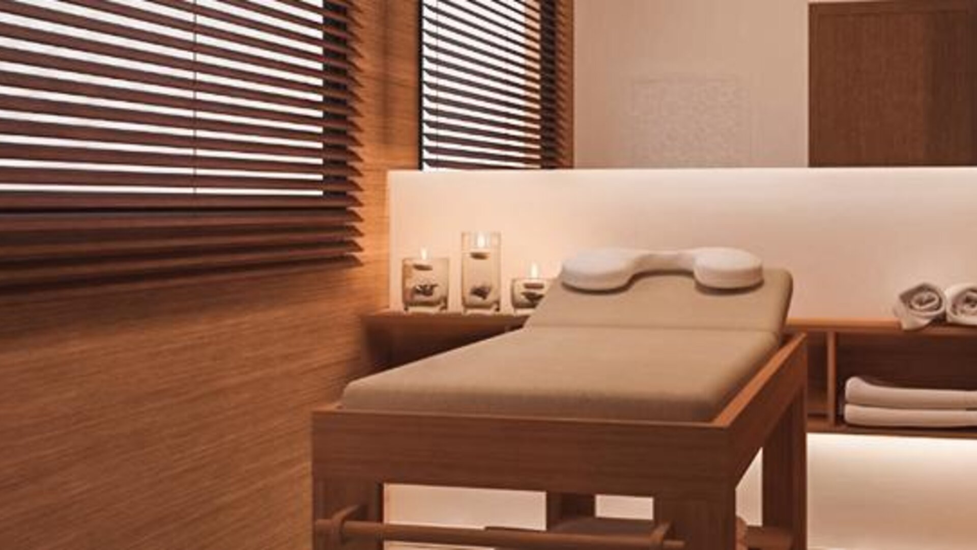Spa treatment room with a padded massage table, folded towels, candles and warm wood-panelled walls at Howard Johnson Plaza Buenos Aires.