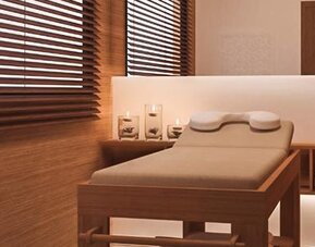 Spa treatment room with a padded massage table, folded towels, candles and warm wood-panelled walls at Howard Johnson Plaza Buenos Aires.