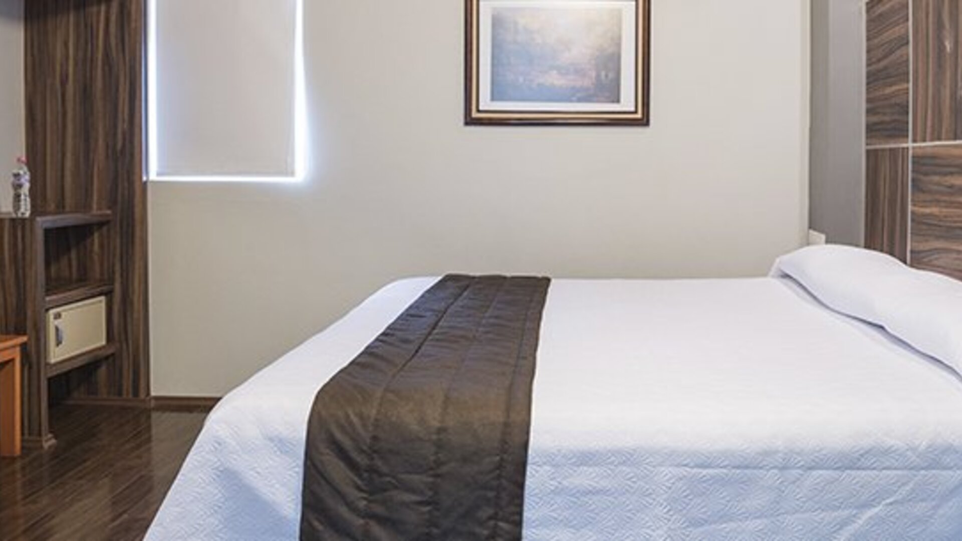 Guest room with a double bed, white bedding, dark wooden headboard and bedside telephone at Hotel Principal.