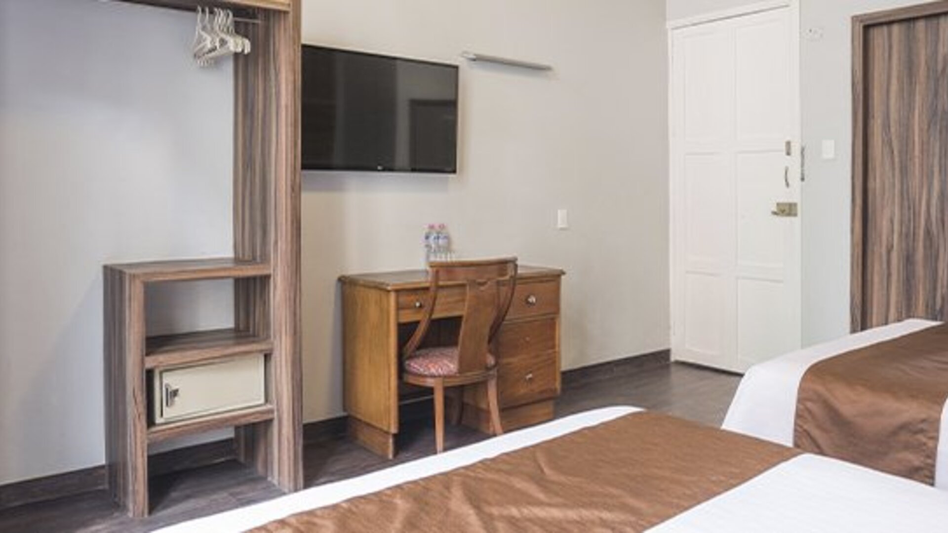 Guest room workspace with a wooden desk, chair and television mounted above the desk at Hotel Principal.