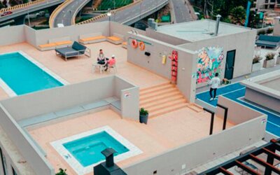 Aerial view of the rooftop terrace featuring a swimming pool, hot tub, seating areas and outdoor sports court at UMA Suites Chía.