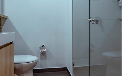 Bathroom with a glass-enclosed shower, white toilet and light wood vanity in a modern, minimalist interior at UMA Suites Chía.