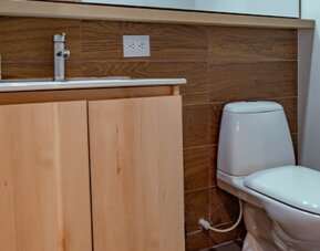 Bathroom with a light wood vanity, white sink, wall-mounted mirror and wood-effect tiled backsplash at UMA Suites Chía.