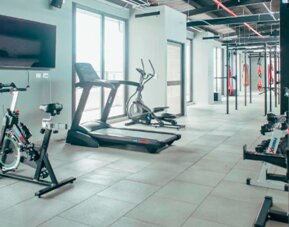 Fitness centre with stationary bikes, treadmills, strength equipment and a wall-mounted television at UMA Suites Chía.