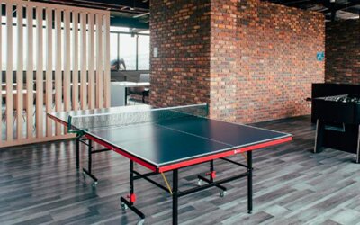 Recreation area with a table tennis table, foosball table, wooden slat partition and exposed brick walls at UMA Suites Chía.
