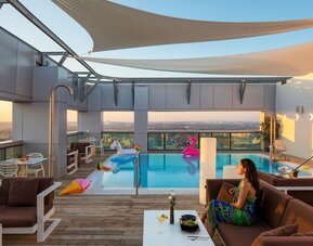Rooftop pool with loungers, shaded seating, inflatable floats and city views at Prima Link.