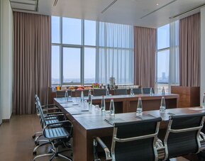 Boardroom with a long conference table, black chairs, bottled water and city views  at Prima Link.