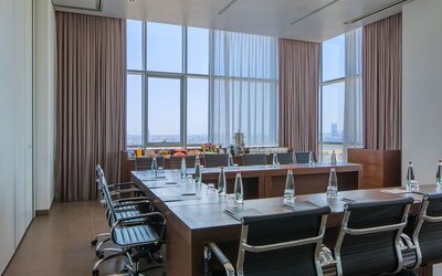 Boardroom with a long conference table, black chairs, bottled water and city views  at Prima Link.