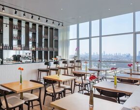 Restaurant with wooden tables, flower vases, wine shelves and panoramic windows at Prima Link.