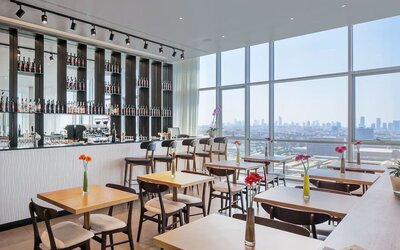 Restaurant with wooden tables, flower vases, wine shelves and panoramic windows at Prima Link.