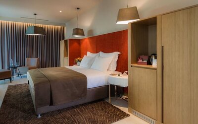 Spacious guest room with a king bed, brown throw, orange headboard and wooden cabinetry at Prima Link.