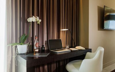 Work desk with an open laptop, notebook, white chair and potted orchid at Prima Link.
