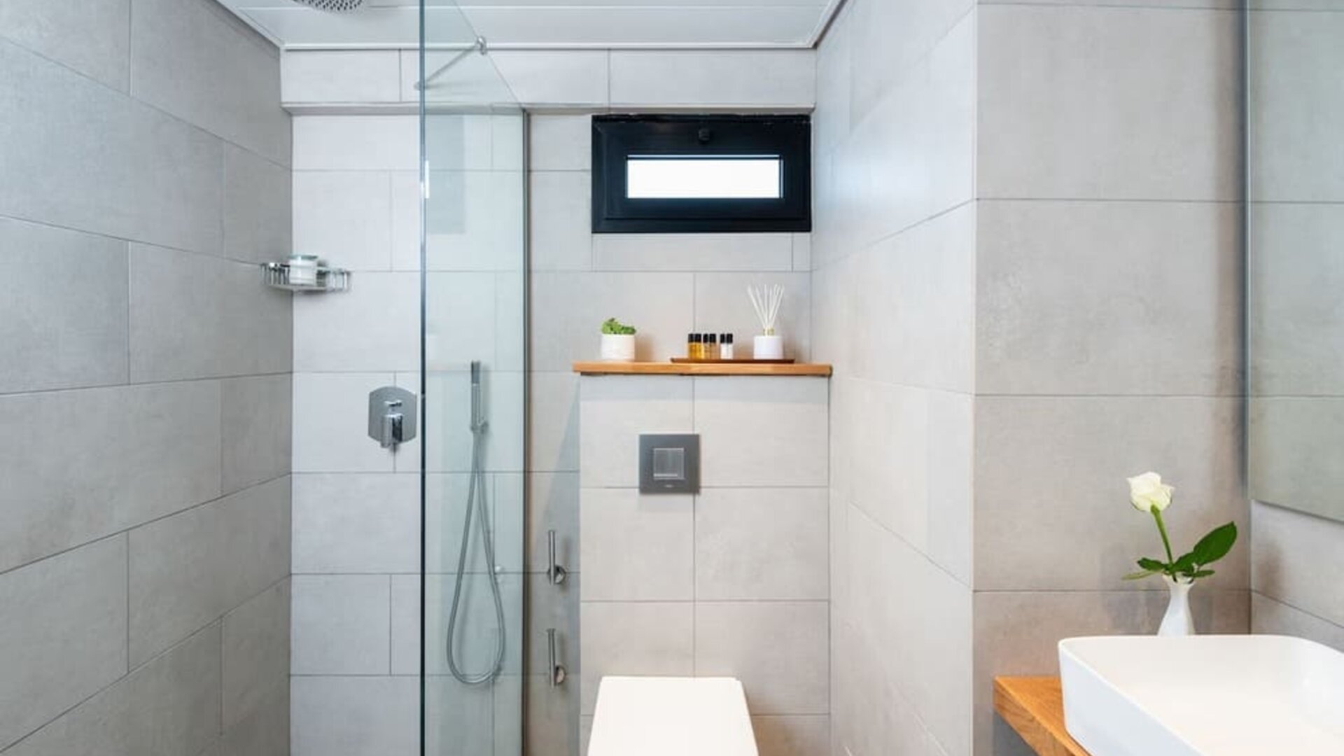 Modern bathroom with a glass-enclosed shower, rainfall showerhead and stone-effect tiles at Prima Galil Tiberias.