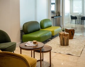 Lobby lounge with contemporary green seating, wooden tables and a bright minimalist interior at Prima Galil Tiberias.