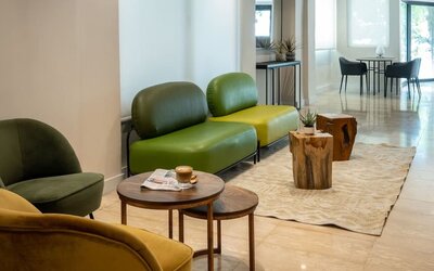 Lobby lounge with contemporary green seating, wooden tables and a bright minimalist interior at Prima Galil Tiberias.