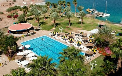 Aerial view of the outdoor swimming pool surrounded by palm trees, sun loungers and landscaped gardens beside the Red Sea at Prima Music Eilat