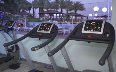 Fitness centre with treadmills overlooking the outdoor pool area at Prima Music Eilat.