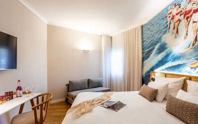 Guest bedroom with a double bed, white curtains and large windows providing natural light at Prima Music Eilat.