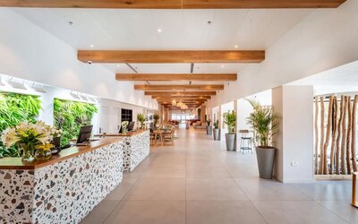 Hotel reception area with a decorative stone-fronted desk, greenery and a long, bright lobby at Prima Music Eilat.