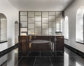 Lobby lounge with black tiled flooring, contemporary seating and gold decorative accents at Lady Stern Hotel.