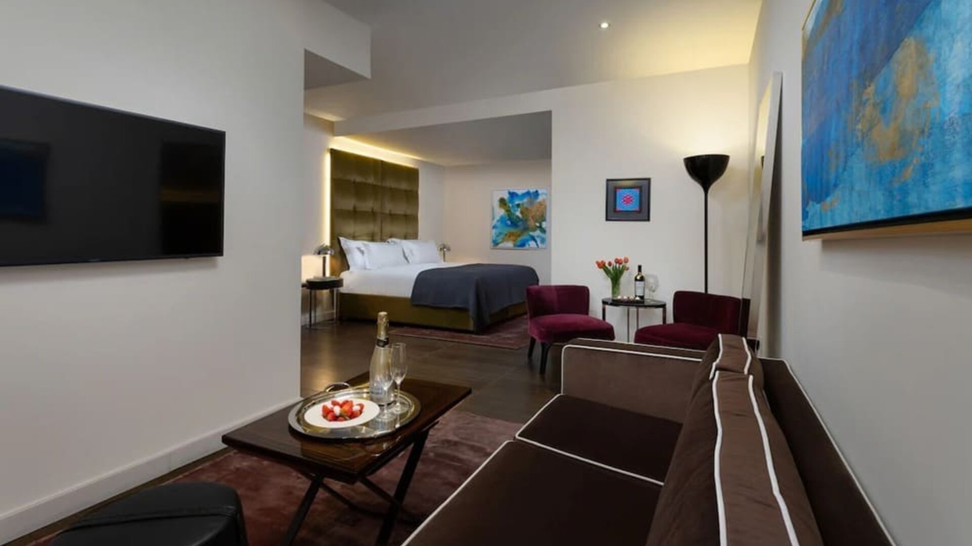 Spacious suite with sofa, coffee table, lounge chairs and separate sleeping area at Lady Stern Hotel.
