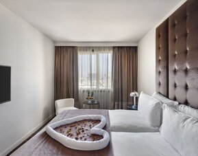 Guest room with king bed, tall upholstered headboard and decorative towel arrangement at Lady Stern Hotel.
