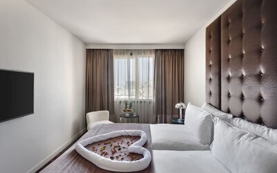 Guest room with king bed, tall upholstered headboard and decorative towel arrangement at Lady Stern Hotel.