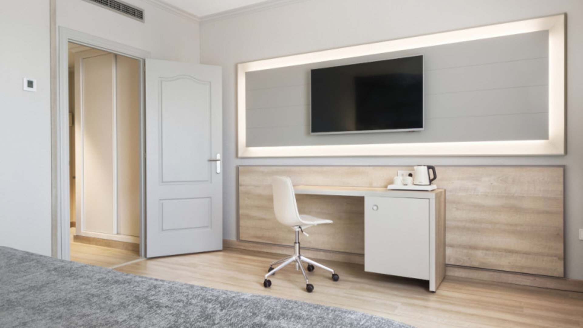 Guest room workspace with a desk, white chair, wall-mounted television and tea-making facilities at Hotel Sallés Ciutat del Prat.