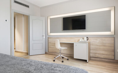 Guest room workspace with a desk, white chair, wall-mounted television and tea-making facilities at Hotel Sallés Ciutat del Prat.