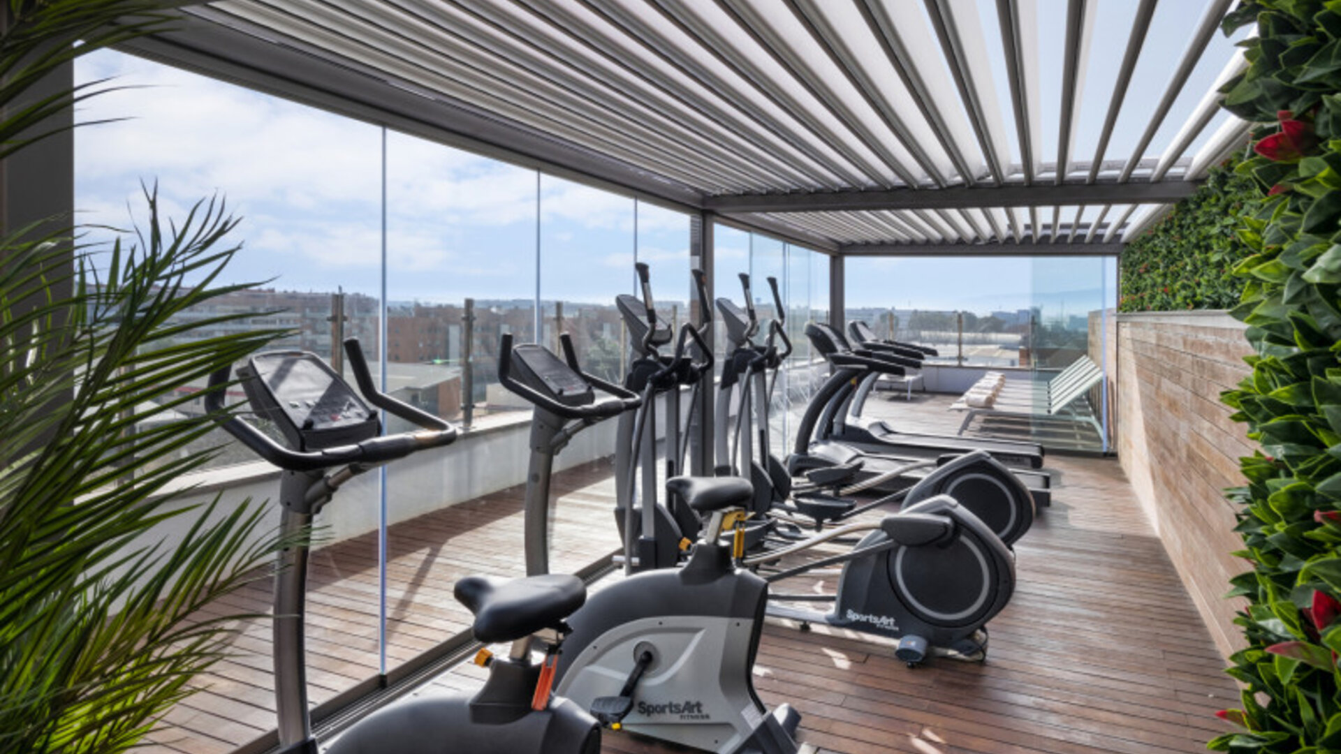 Rooftop fitness centre equipped with stationary bikes, treadmills and exercise machines beside glass railings at Hotel Sallés Ciutat del Prat.