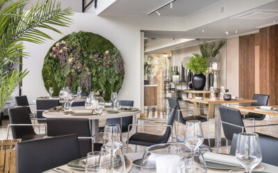 Restaurant dining room with wooden tables, black chairs, place settings and warm illuminated wall panels at Hotel Sallés Ciutat del Prat.