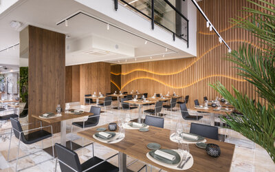 Restaurant seating with round tables, dark chairs and a circular vertical garden mounted on the wall at Hotel Sallés Ciutat del Prat.