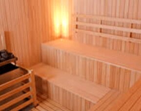 Wooden sauna with tiered benches, stone heater and folded white towels at Design Suites Buenos Aires.