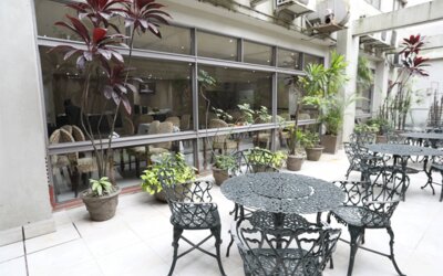 Outdoor terrace with decorative black metal tables and chairs beside large windows and potted plants at HR Esmeralda Luxor.