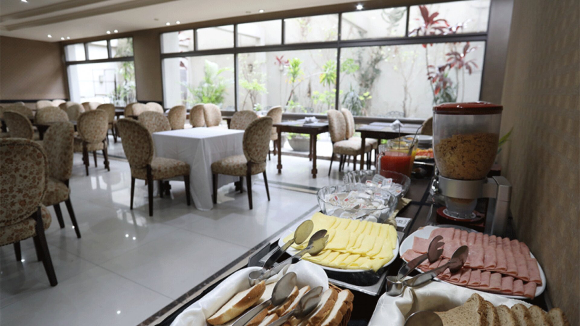 Breakfast buffet displaying sliced cheese, cold meats, bread and cereal beside dining tables at HR Esmeralda Luxor.