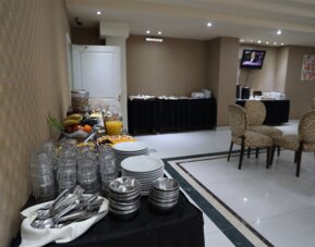 Breakfast buffet with stacked plates, glasses, cutlery, fresh fruit, juice and serving tables at HR Esmeralda Luxor.