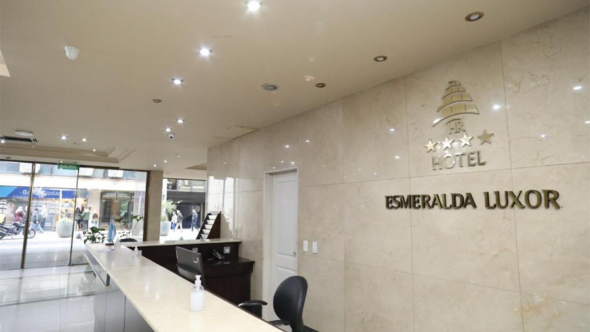 Hotel reception with marble counter, black workstation and wall-mounted HR Hotel Esmeralda Luxor signage.