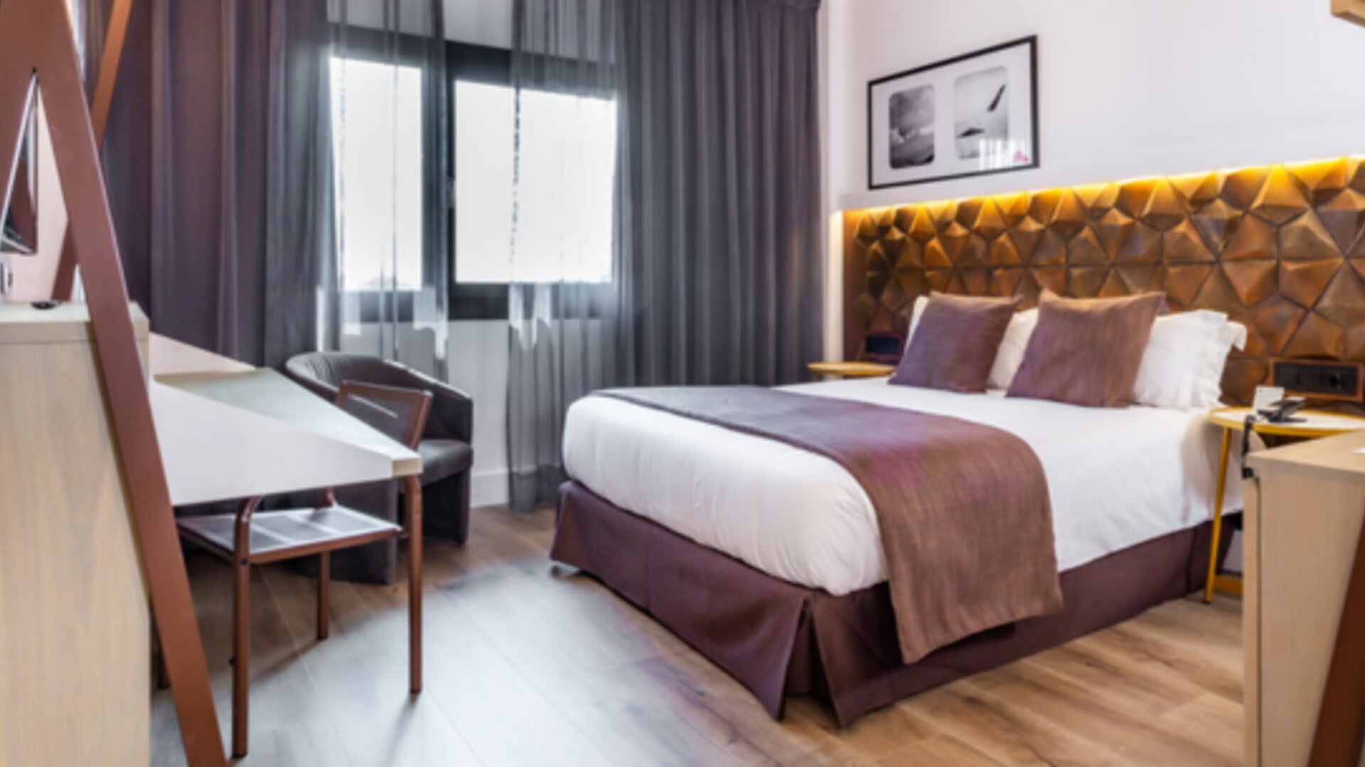 Guest room with king bed, brown accent bedding, wooden desk, lounge chair and floor-to-ceiling curtains at Hotel Best Western PLUS Alfa Aeropuerto.g