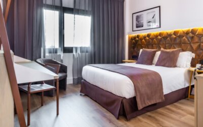 Guest room with king bed, brown accent bedding, wooden desk, lounge chair and floor-to-ceiling curtains at Hotel Best Western PLUS Alfa Aeropuerto.g