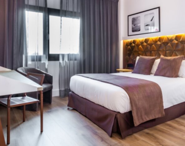 Guest room with king bed, brown accent bedding, wooden desk, lounge chair and floor-to-ceiling curtains at Hotel Best Western PLUS Alfa Aeropuerto.g