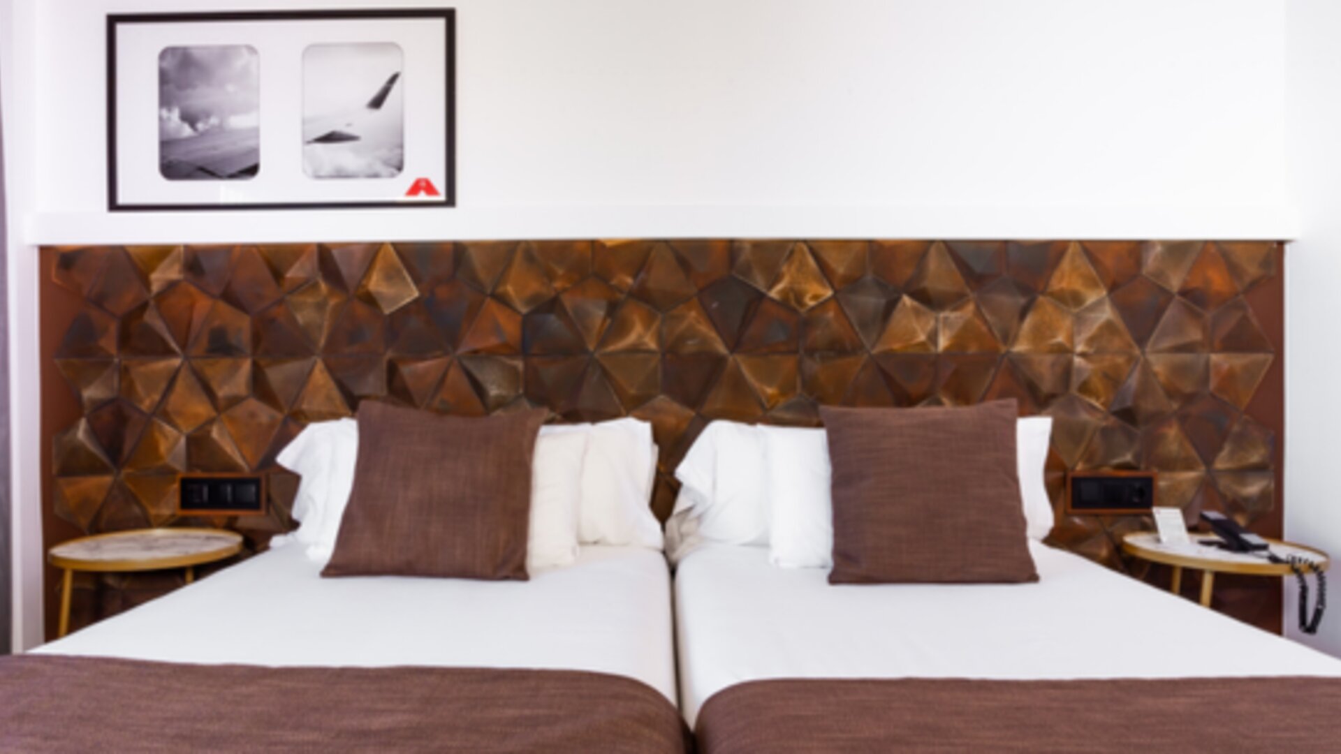 Guest room with white bed linens, brown accent cushions, geometric padded headboard and bedside tables at Hotel Best Western PLUS Alfa Aeropuerto.