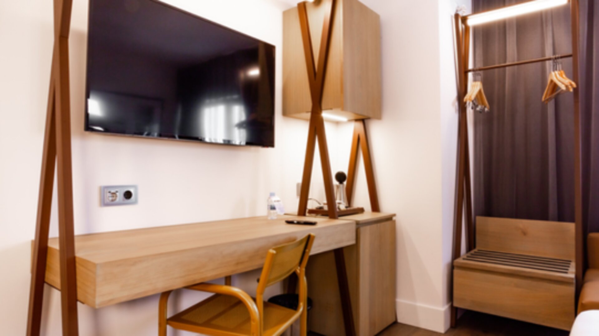 Guest room workspace with wooden desk, chair, wall-mounted television, open wardrobe and hanging clothes at Hotel Best Western PLUS Alfa Aeropuerto.