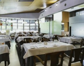 Restaurant dining room with white tablecloths, dark wooden chairs, glass walls and neatly arranged place settings at Hotel Best Western PLUS Alfa Aeropuerto.