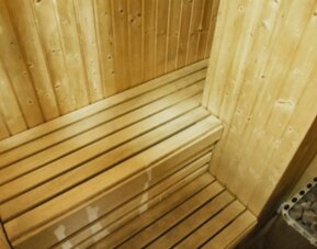 Wooden sauna with tiered benches and a stone heater in the corner at Hotel Best Western PLUS Alfa Aeropuerto.