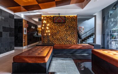Hotel lobby with brown leather seating, geometric feature wall, staircase and large windows overlooking greenery at Hotel Best Western PLUS Alfa Aeropuerto.
