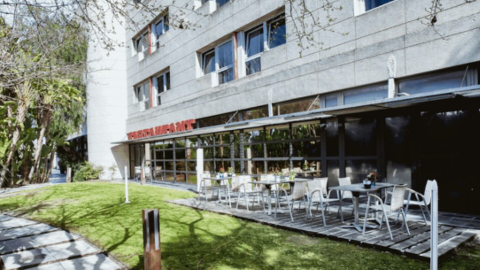 Outdoor restaurant terrace with white tables and chairs beside a landscaped lawn and modern hotel building at Hotel Best Western PLUS Alfa Aeropuerto.